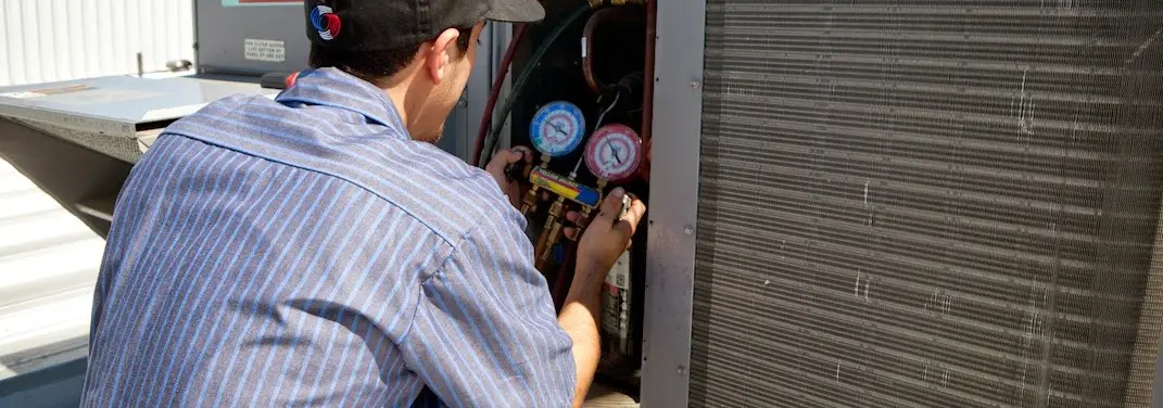 HVAC technician servicing a condenser unit in Laurel